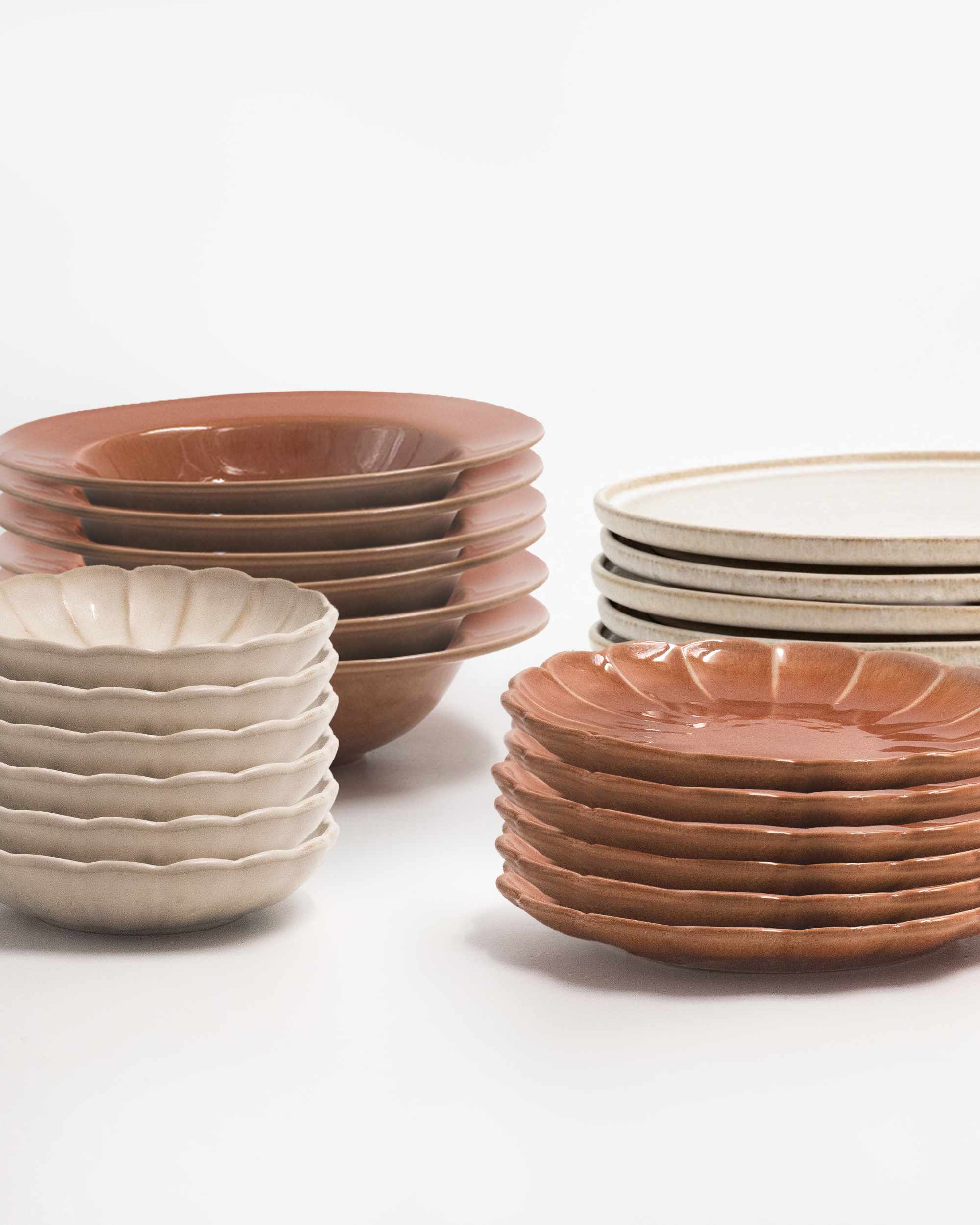 Servis i beige och terracotta i fyra staplar. De mindre tallrikarna har en blomsilhuett och tillsammans skapar de en komplett servis. Fotograferad mot en vit bakgrund