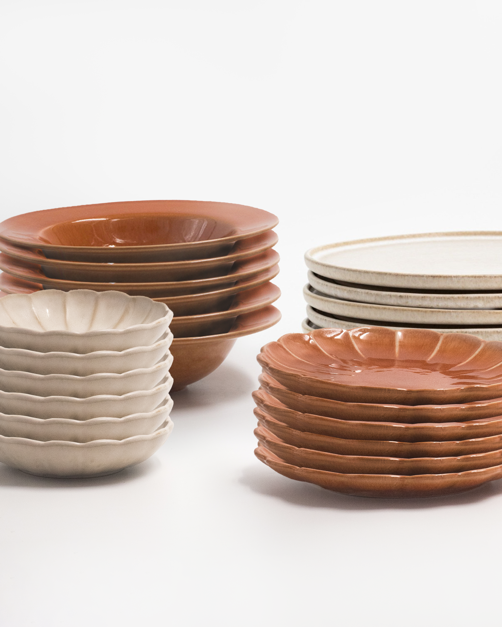 Servis i beige och terracotta i fyra staplar. De mindre tallrikarna har en blomsilhuett och tillsammans skapar de en komplett servis. Fotograferad mot en vit bakgrund